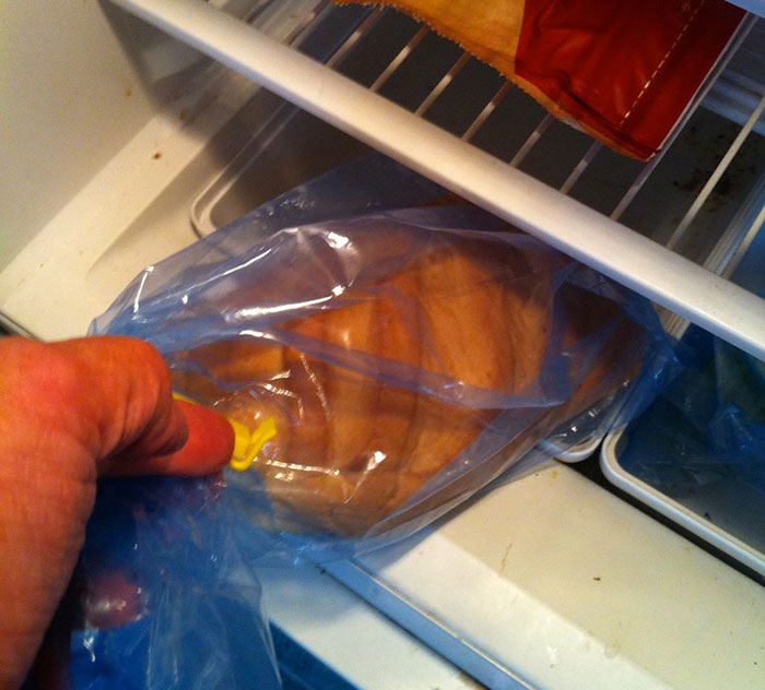 Raw chicken sealed in a plastic bag inside a refrigerator, illustrating washing chicken cooking myths debate.