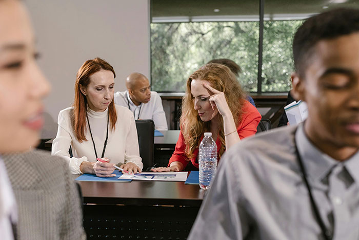 A woman and coworker discussing documents in a meeting room, highlighting issues affecting workplace morale. - 6