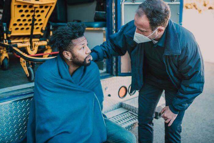 First responders attending to a person wrapped in a blanket by an emergency vehicle during a strange call.