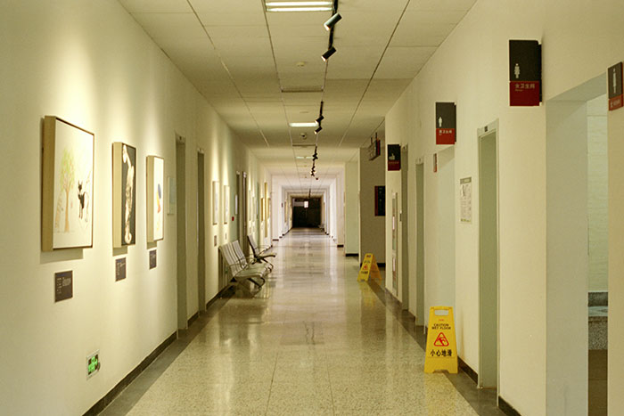 Hospital corridor with artwork on walls and caution signs, reflecting a medical environment where professionals monitor patient conditions.