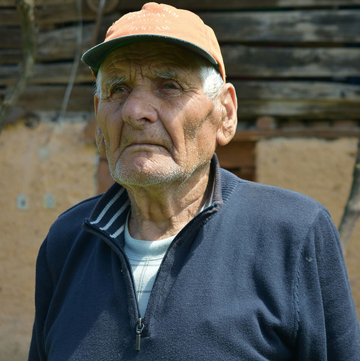 Elderly man wearing a cap and navy jacket, representing inspiring medical professionals surprised by patient survival stories.