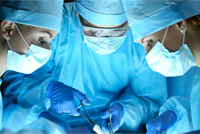 Surgeons in blue scrubs and masks perform a complex operation in a sterile environment, highlighting creepy and terrifying facts.