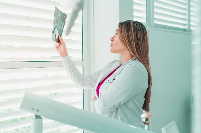 Woman in a white coat examining an X-ray by a window, illustrating creepy and terrifying facts concept.