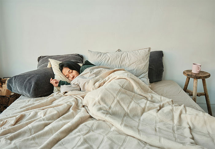 Person sleeping peacefully in bed covered with blankets, illustrating contrast to creepy and terrifying facts theme.