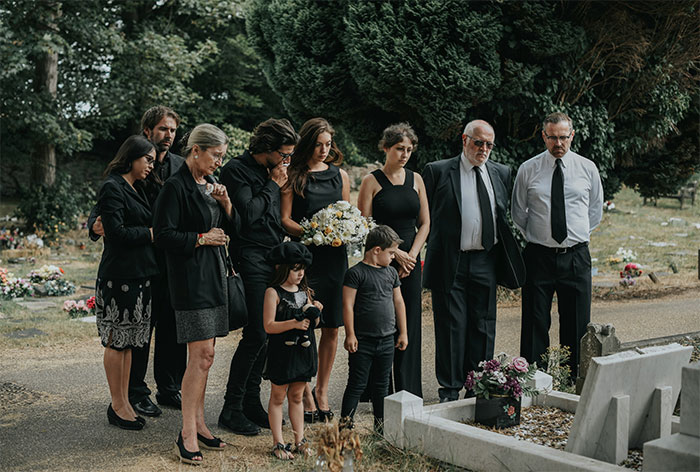 Group of mourners dressed in black at a graveyard, evoking creepy and terrifying facts about death and loss.