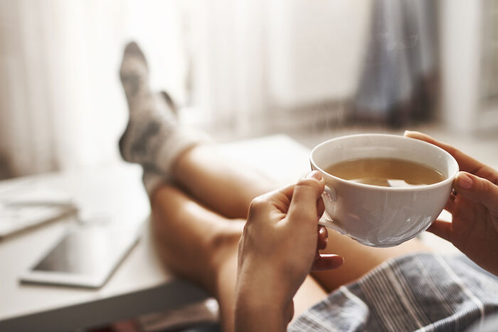 Person relaxing at home in cozy socks, holding a warm cup enjoying simple things that improve life comfort and happiness. - 21