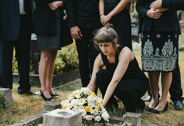 Woman grieving at a gravesite, surrounded by mourners, reflecting on relationship struggles and breakup reasons.
