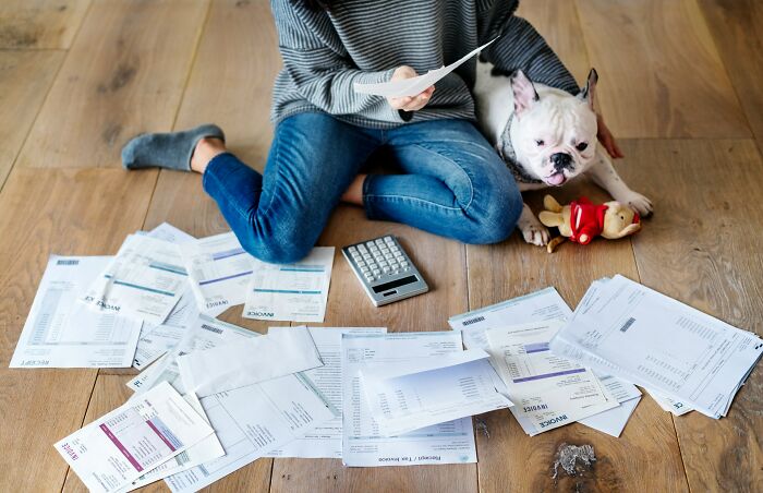 Person sitting on floor with paperwork and calculator, demonstrating calm communication skills during financial tasks.
