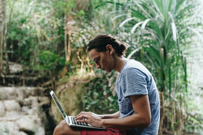 Young person typing on a laptop outdoors surrounded by nature, reflecting stories from people who ran away from home. - 10
