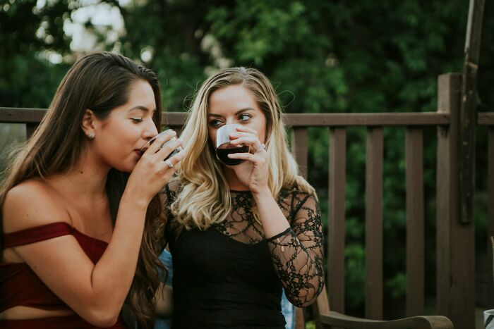 Two women drinking wine outdoors, illustrating social behaviors linked to toxic femininity traits. - 7