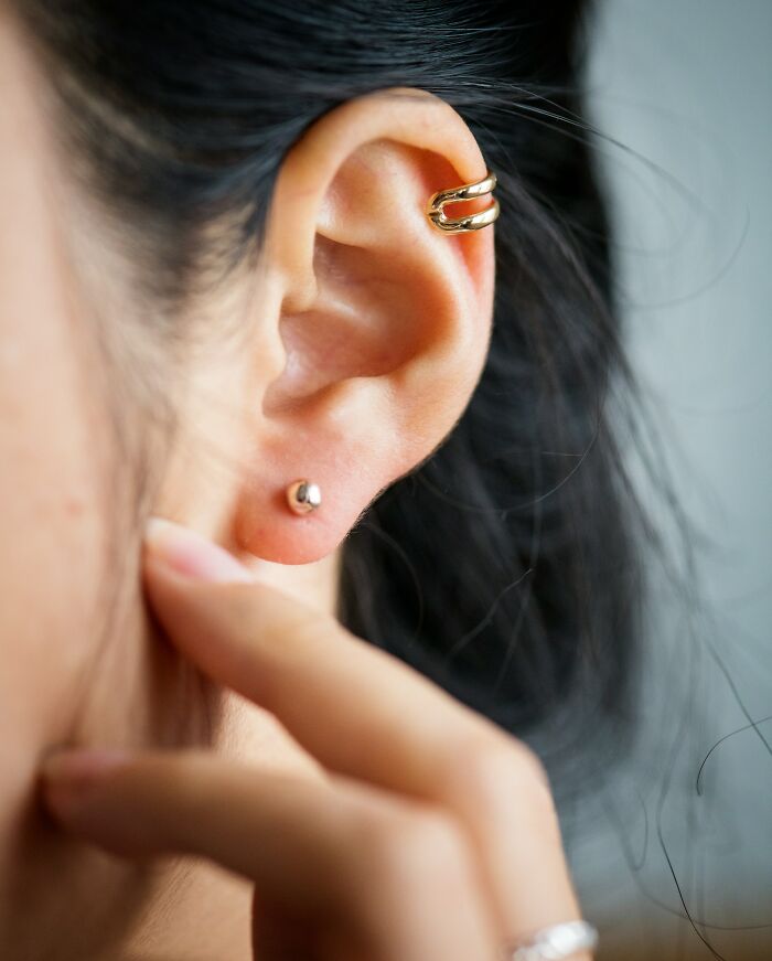 Close-up of ear with two gold earrings highlighting mysterious body quirks that intrigue people worldwide.