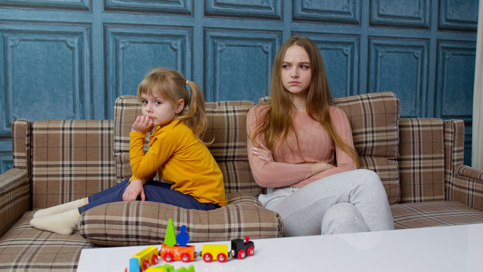 Two girls sitting apart on a couch, showing tension and refusal to accept stepmom in a family setting. - 14