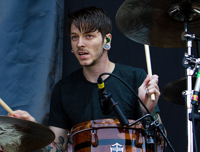 Drummer performing live on stage with drumsticks, surrounded by cymbals and microphones, stars lost this year concept.