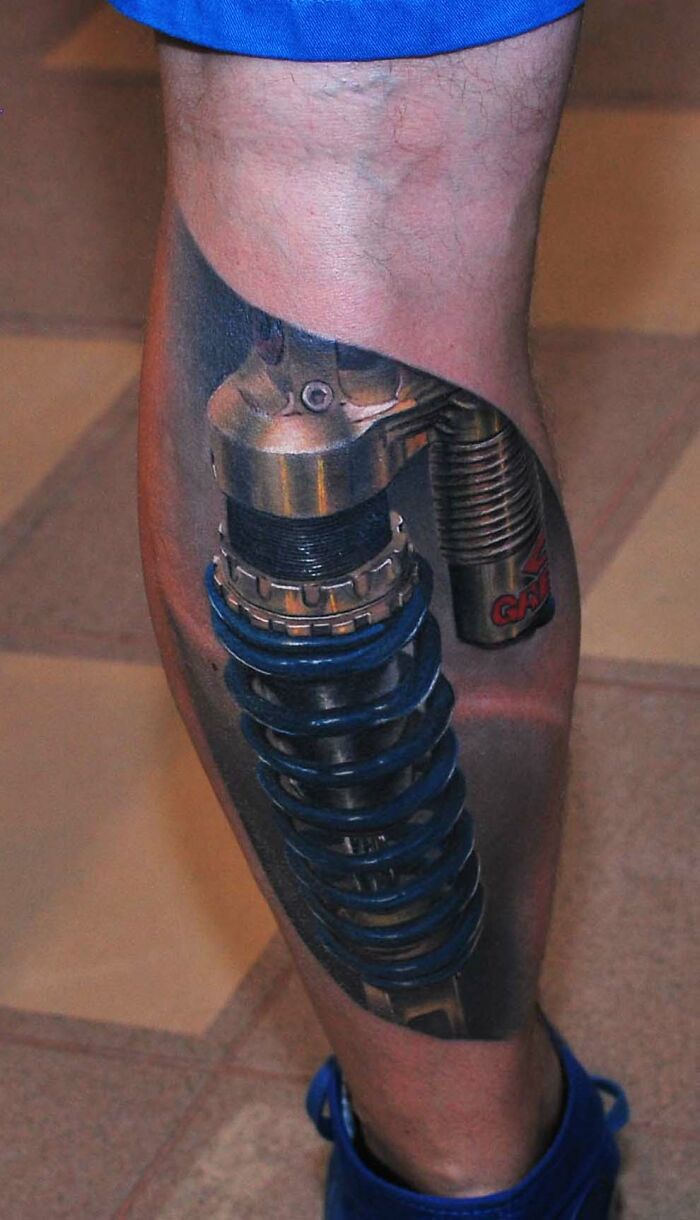 3D mechanical leg tattoo with blue spring detail on a person's calf, one of the best tattoos hitting the like button.
