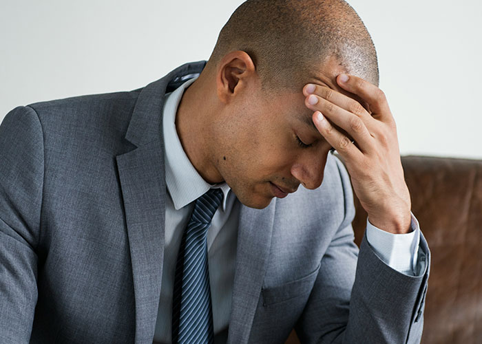 Upset man in a gray suit holding his forehead, expressing frustration related to family concerns and custody issues.