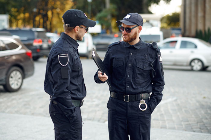 Two police officers in uniform discussing a case outdoors, representing daycare calling CPS after custody no-shows. Two police officers in uniform discussing a case outdoors, representing daycare calling CPS after custody no-shows.