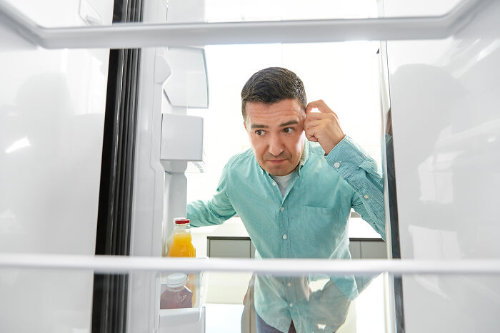 Man in a teal shirt peering into a refrigerator, illustrating deaf people reveal surprisingly silent things concept.