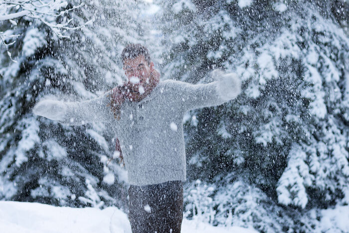 Person in a snowy forest throwing snow in the air, illustrating a scene related to deaf people and silent experiences.