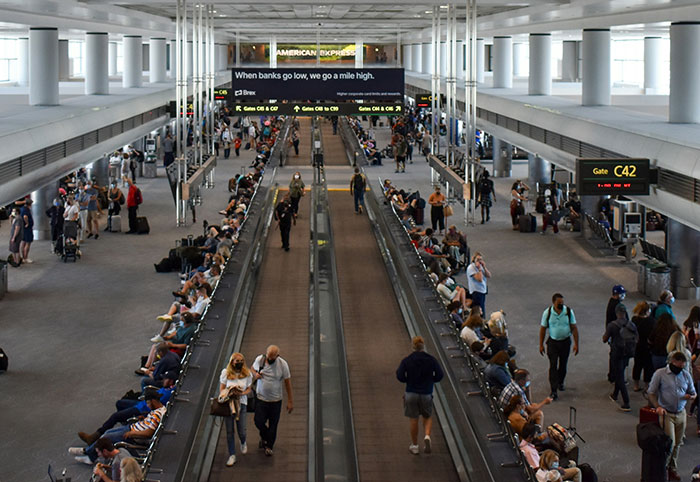 Busy airport terminal with travelers and United Airlines crew amid trafficking accusations involving foster dad and Latina daughters.