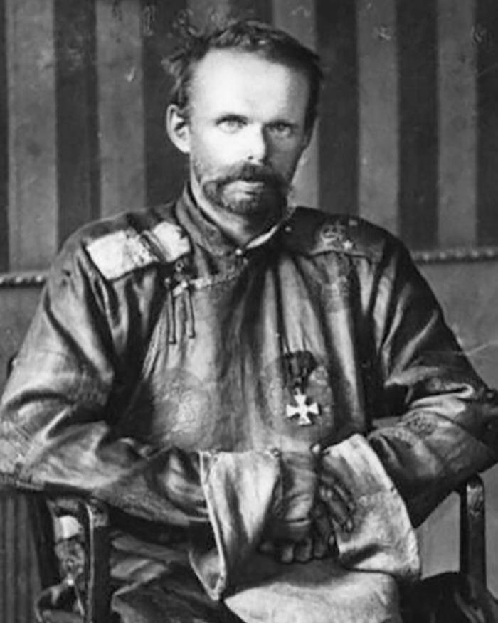 Black and white historic photo of the last king of Mongolia in traditional attire with medals seated and posing.