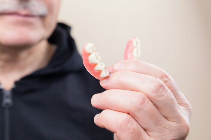 Elderly person holding dentures, illustrating one of the items found on patients that made medical professionals gasp.