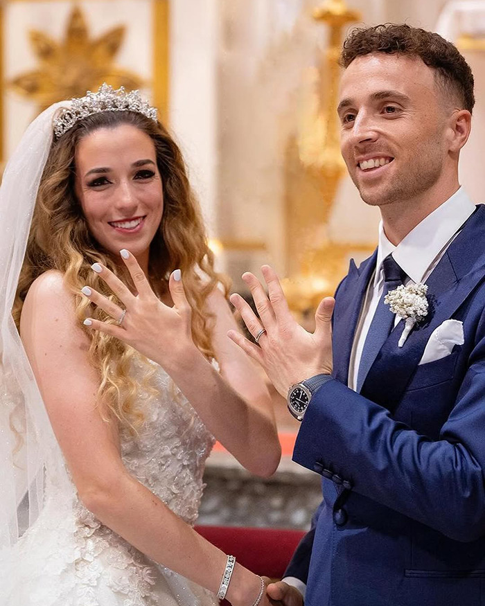 Bride and groom smiling and showing wedding rings, a reminder of life's fragility in a heartfelt moment.