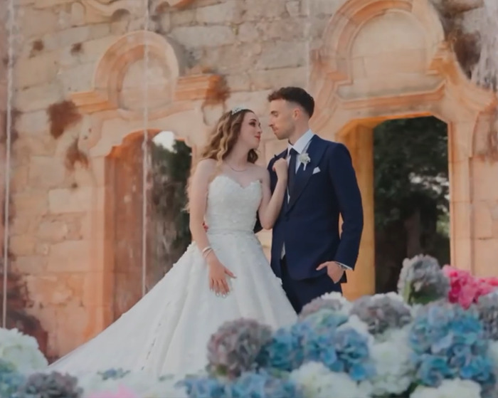 Bride and groom in wedding attire standing close near ancient stone arches, symbolizing reminder of life's fragility.