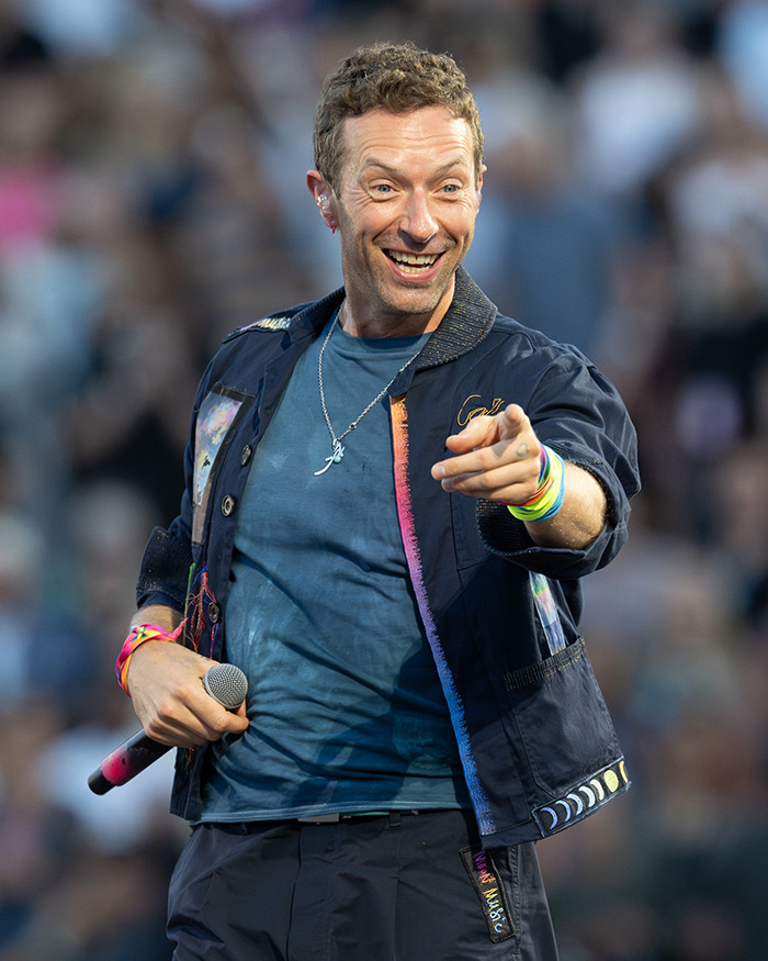 Male performer wearing colorful bracelets and holding microphone during live concert, related to Disgraced CEO Andy Byron lawsuit news.
