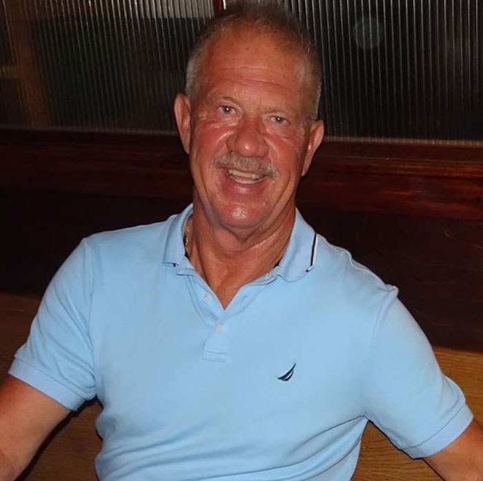 Man in light blue polo shirt smiling while seated indoors, unrelated to girl's fall from Disney cruise ship incident