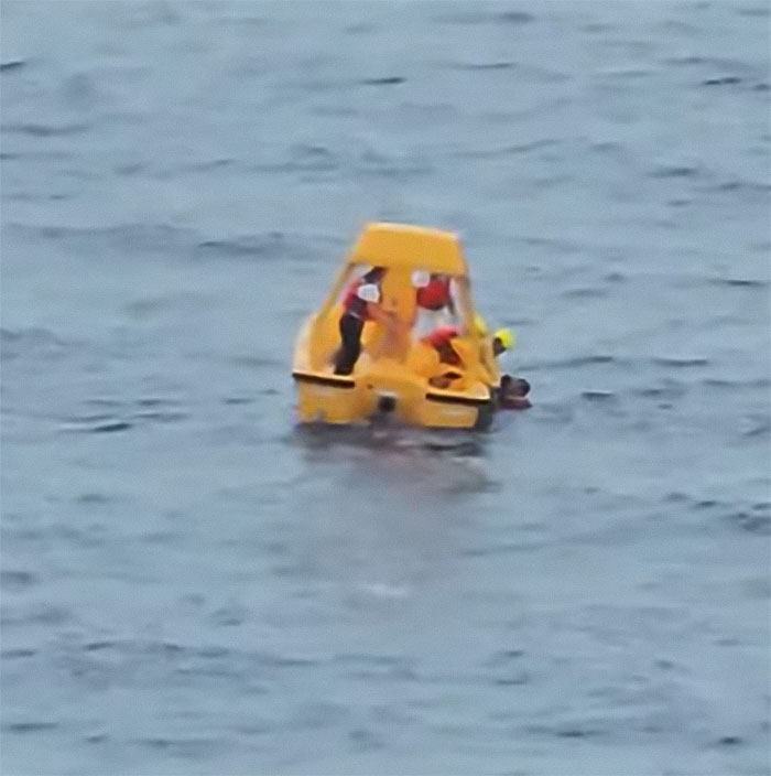 Rescue team in a yellow boat assisting after a girl's horrifying fall from a Disney cruise ship in open water.