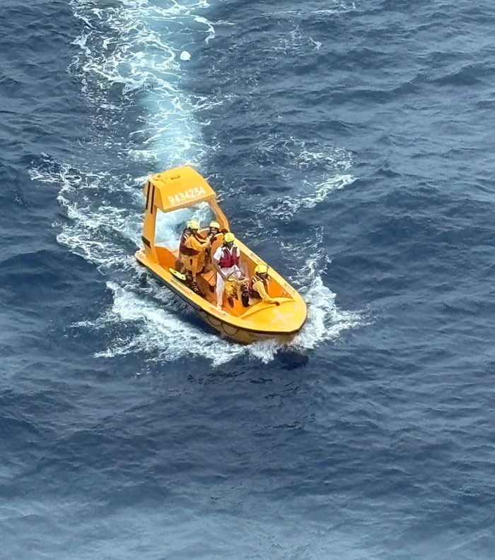 Rescue team on a small yellow boat responding to a girl's fall from Disney cruise ship in open sea waters.