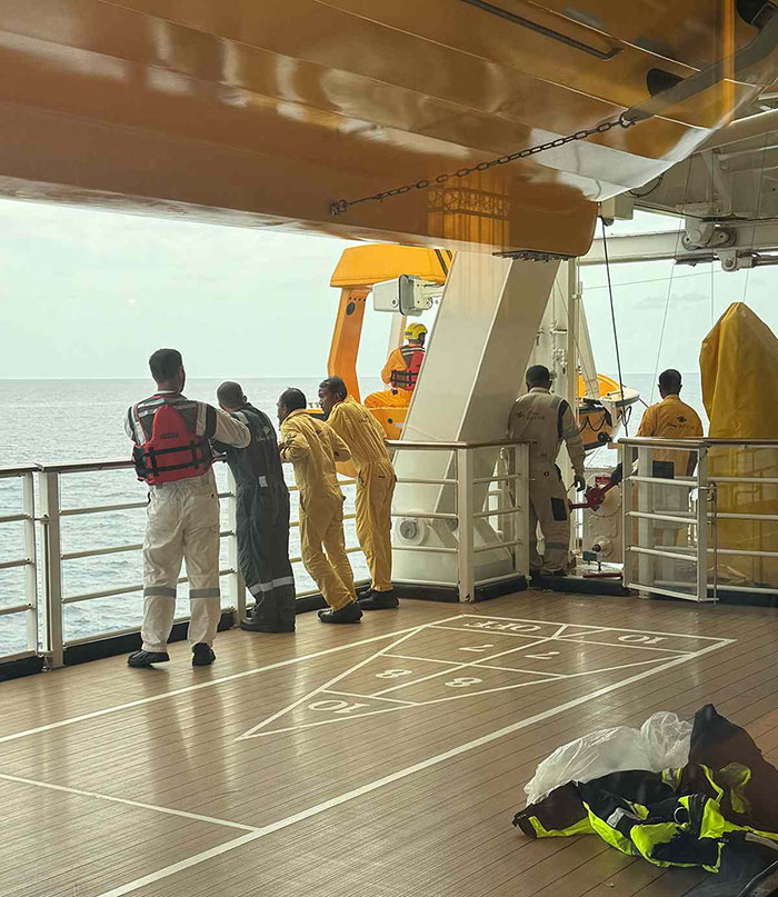 Crew members on Disney cruise ship deck looking out to sea during response to girl's fall incident eyewitness investigation.