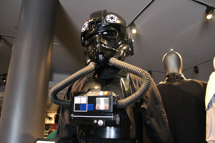 Black Star Wars pilot costume with tubes displayed in a dimly lit room, representing a once adored Disneyland attraction.