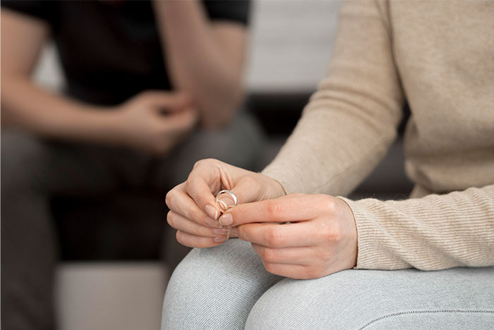 Woman holding wedding rings, appearing heartbroken while discussing polyamory with husband after one year of marriage. - 49