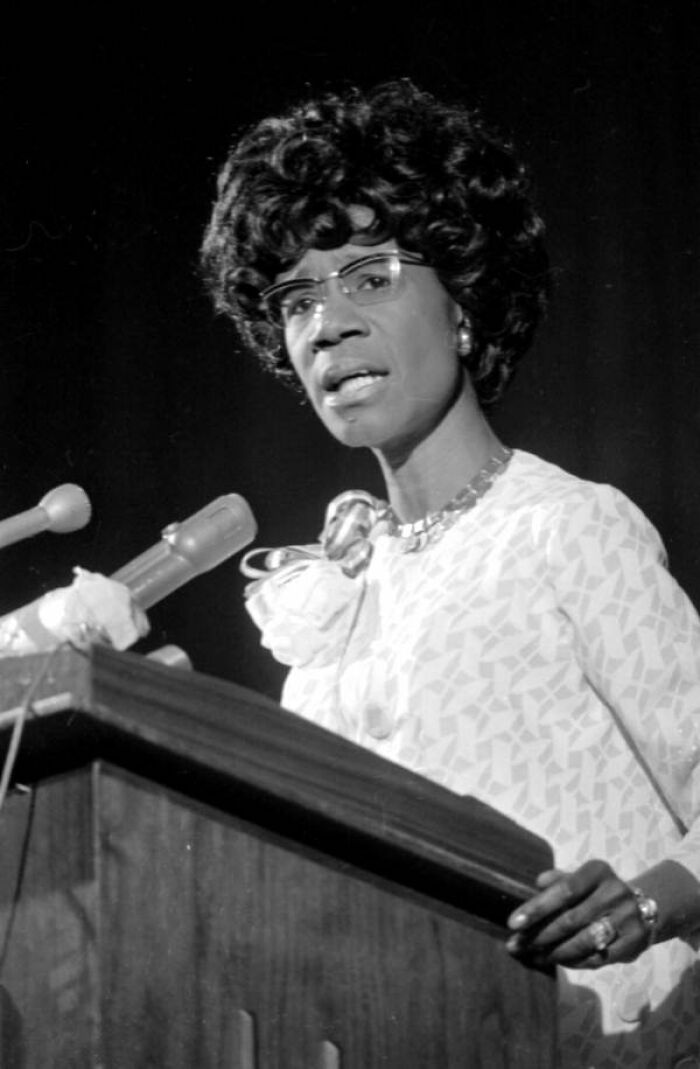 Woman in Florida speaking at a podium with microphones, showcasing women breaking barriers in the 1970s.