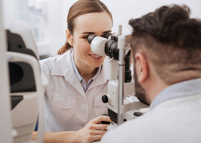 Female doctor examining patient’s eye using medical equipment, related to bizarre medical cases with skin conditions.