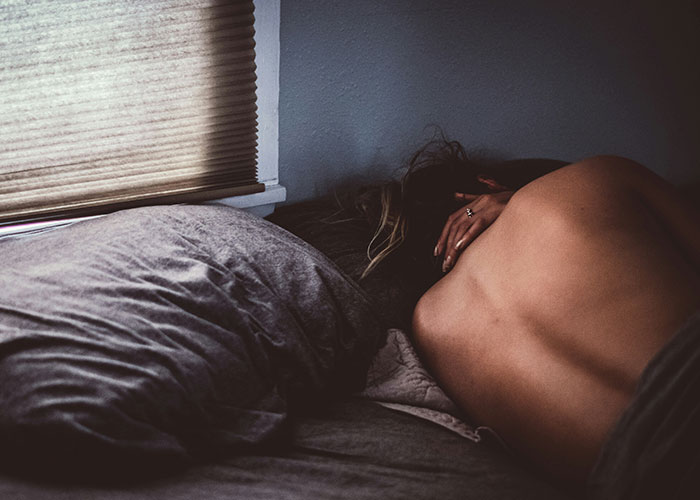 Person lying face down on a bed in a dimly lit room, illustrating patients who delayed help with shocking consequences. - 2