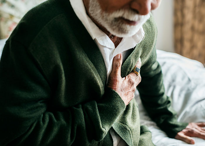 Elderly man clutching chest in pain, illustrating patients delaying help with shocking medical consequences. - 21