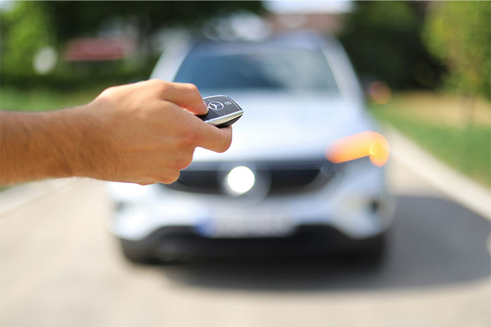 Person holding a car key fob in front of a white vehicle, illustrating moments people realized they were doing something wrong. - 17