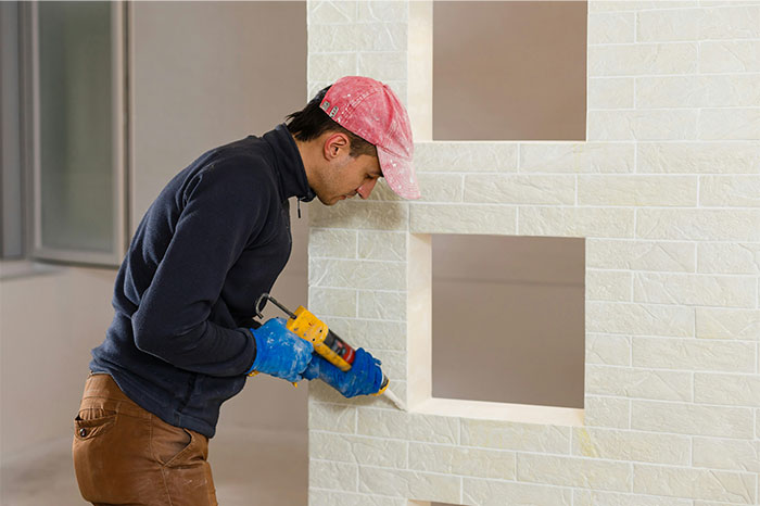 Man wearing a red cap applying sealant with a caulking gun on a tiled wall, illustrating a wrong way to do a task moment - 40