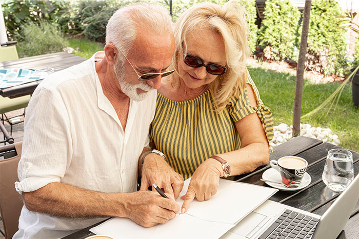 Older couple outdoors looking at papers and laptop, realizing they were doing something the wrong way together. - 31