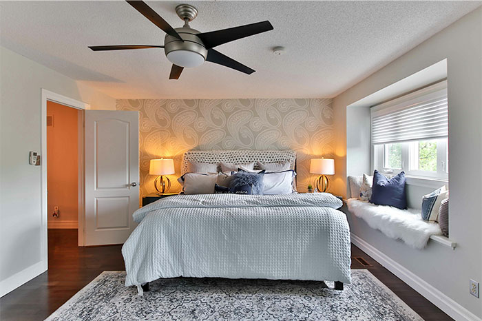 Modern bedroom with neutral tones, patterned wallpaper, and cozy pillows illustrating common home design mistakes. - 2