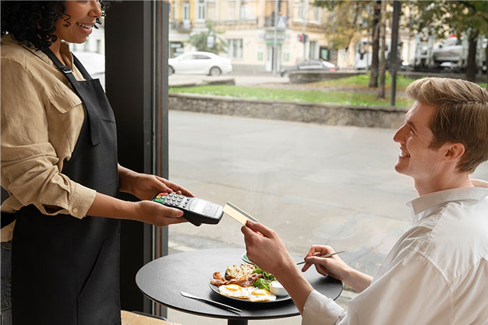 Customer handing credit card to waitress with card reader in a cafe, illustrating people realizing mistakes in everyday tasks. - 28