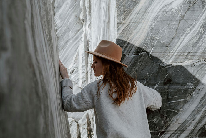 Woman wearing a hat and sweater carefully navigating between two large rock walls, reflecting a moment of realizing a wrong way. - 36