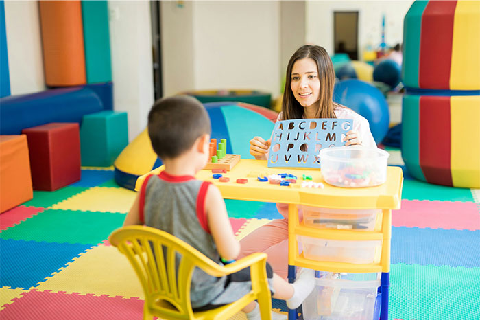 Woman teaching a child alphabet letters in a colorful room, illustrating moments of realizing the wrong way to do things. - 11