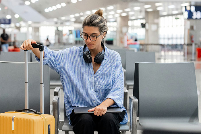 Woman at airport with yellow suitcase and headphones, reflecting on moments she realized she was doing something wrong. - 39
