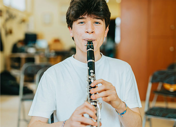 Teen boy playing clarinet indoors, capturing a moment of realizing they were doing something the wrong way. - 34
