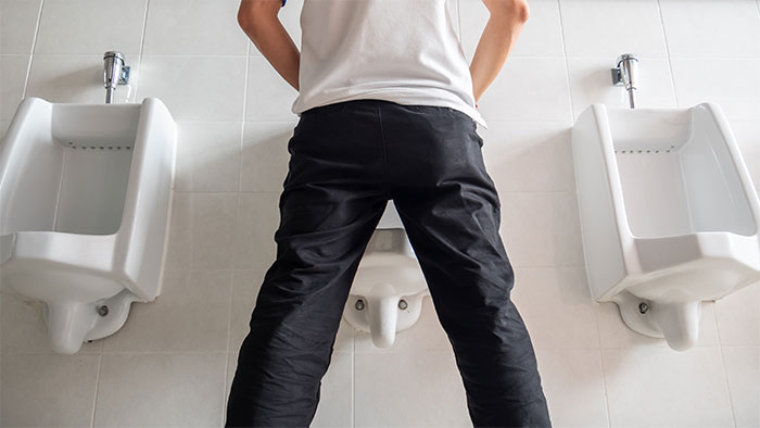 Man standing incorrectly at urinals in a public restroom, illustrating a moment of doing something the wrong way. - 41