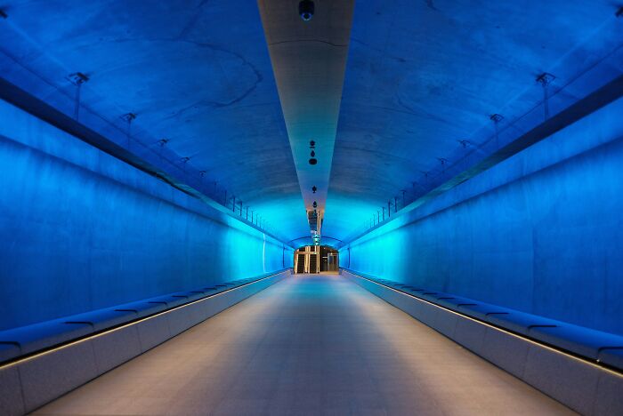 Blue-lit tunnel interior with smooth walls and ceiling, showcasing a futuristic and symmetrical design, no people visible. - 22