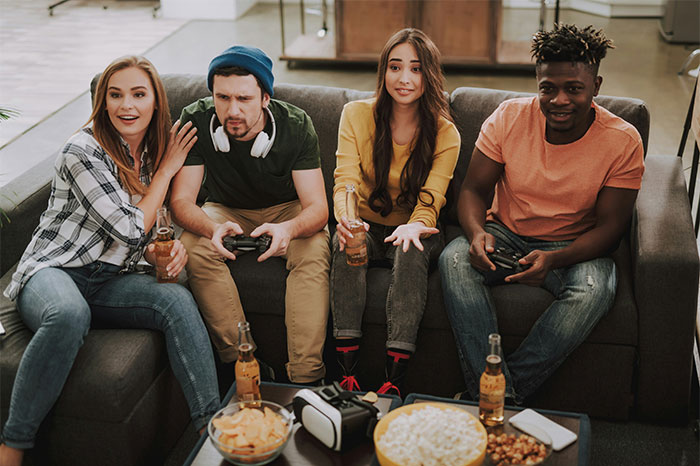Four friends on a couch playing video games and drinking beer, showing a moment of deciding to stop helping others out. - 7